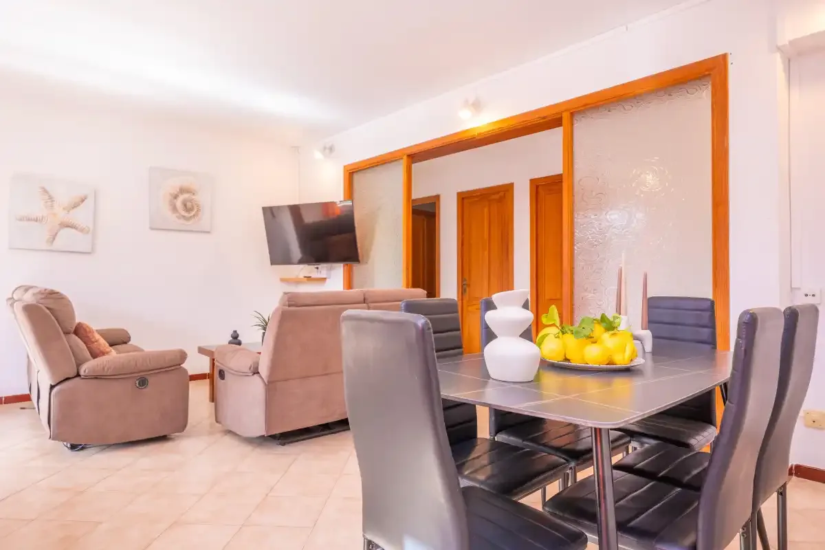 Sala de estar y comedor con asientos alrededor de una mesa y un televisor.