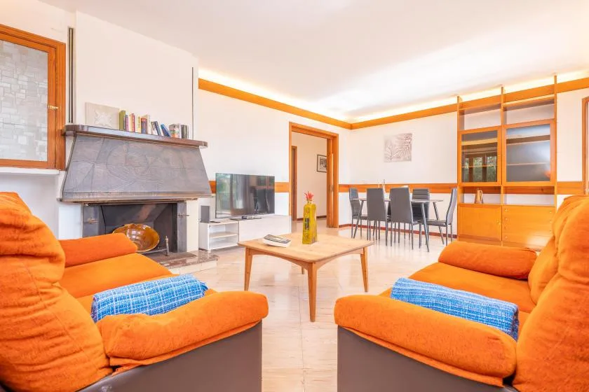 Una luminosa sala de estar y comedor con asientos naranjas y una mesa.