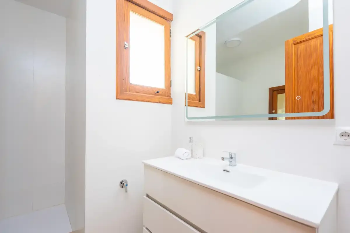 Un baño luminoso con un lavabo blanco bajo un espejo grande.