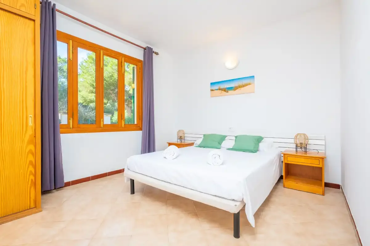 Un dormitorio luminoso con una cama doble y una ventana grande.