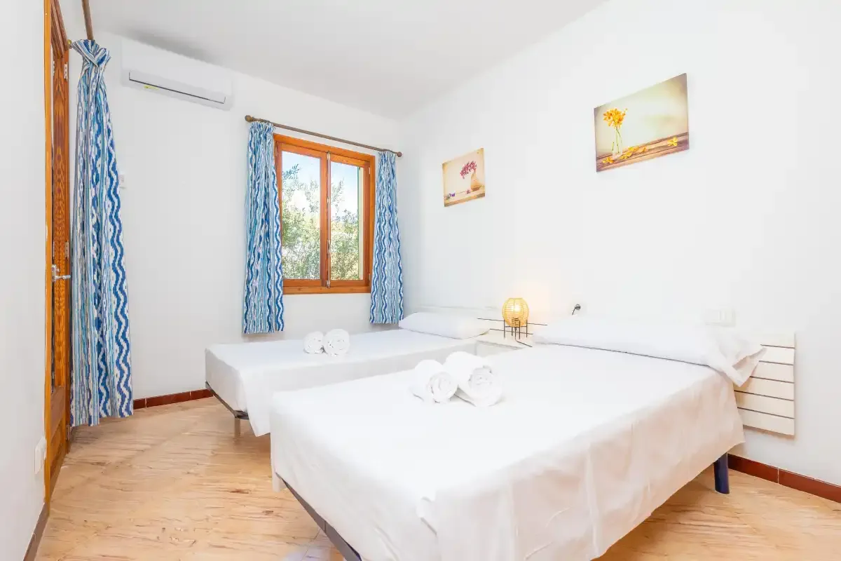 Un dormitorio luminoso con dos camas y cortinas azules en la ventana.