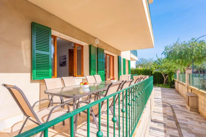 Una terraza con asientos al aire libre junto a ventanas con persianas verdes.