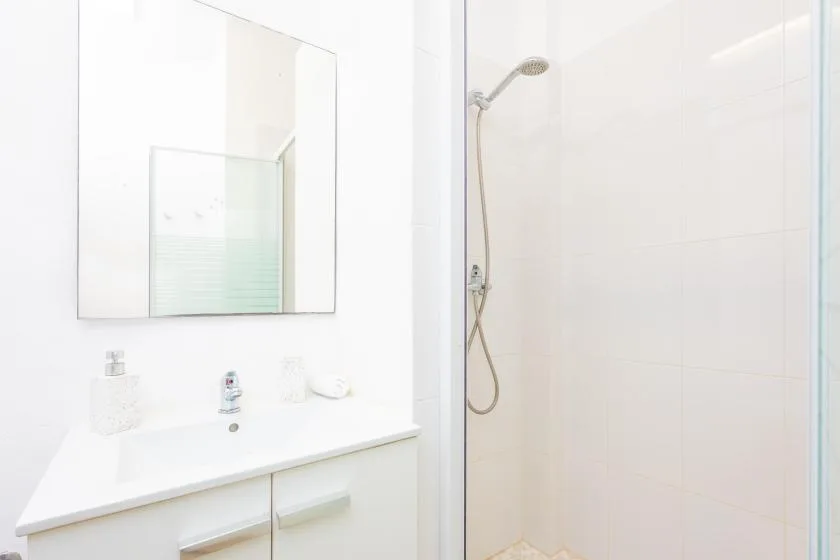 Un baño luminoso con lavabo y ducha de cristal.