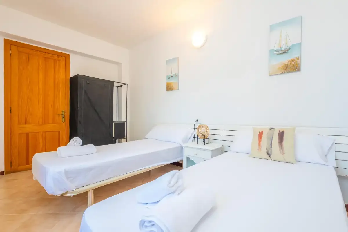 Un dormitorio con dos camas individuales, ropa de cama blanca y cuadros náuticos.