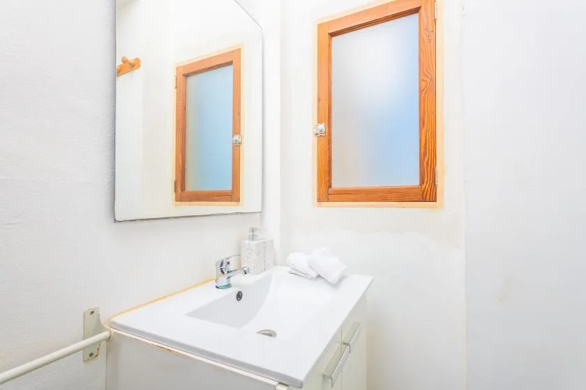 Un lavabo de baño con espejo está junto a una ventana.