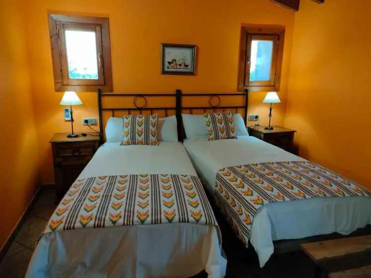 A bedroom with two beds, patterned bedding, and matching bedside lamps.