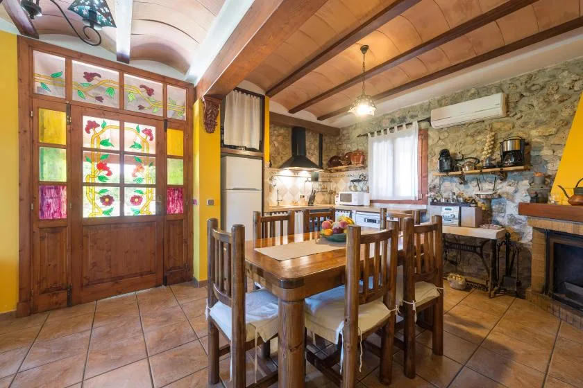 A rustic dining area with a wooden table and stained-glass door.