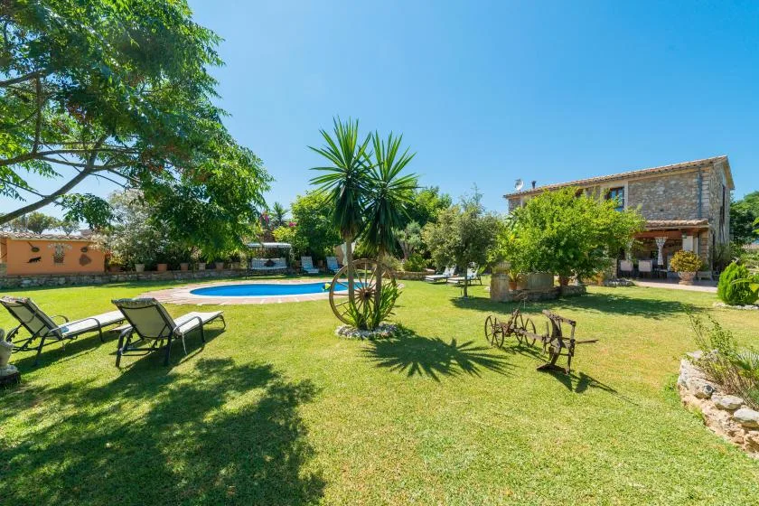 A landscaped garden with a swimming pool, trees, and outdoor seating.