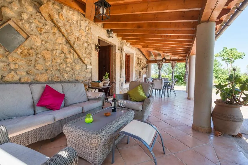 A covered stone patio with seating and a long outdoor dining table.