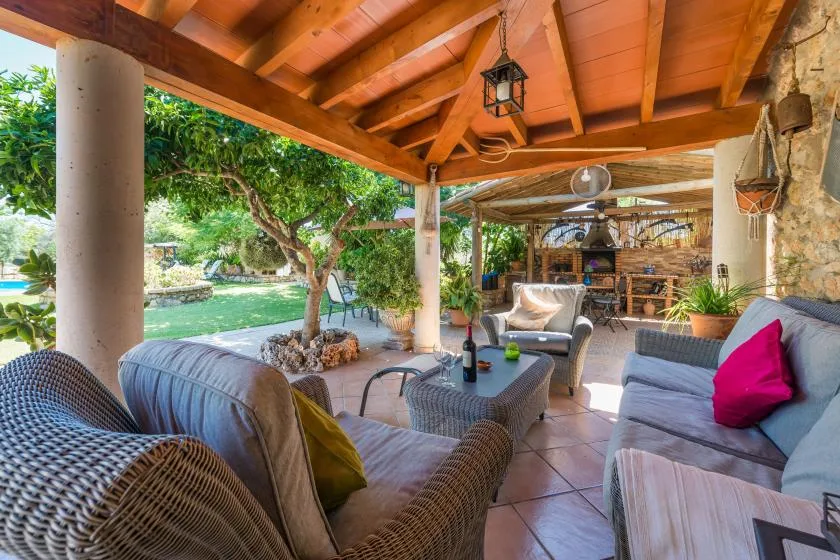 A covered outdoor seating area opens onto a leafy garden.
