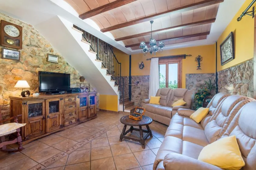 A living room with cushioned seating, a coffee table, and a staircase.