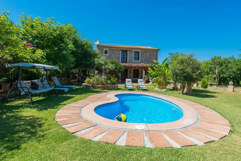 A garden courtyard with a round swimming pool and a house in the background.