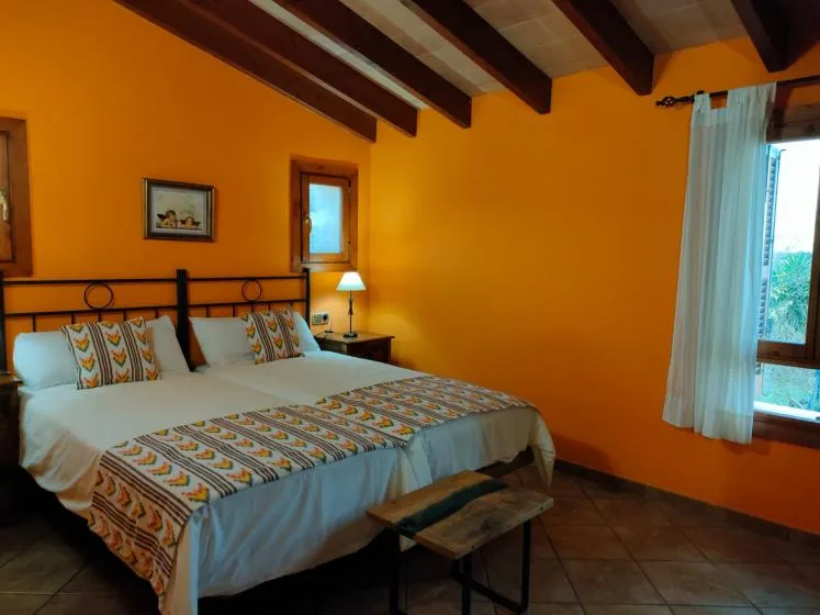 A bedroom with a bed, patterned bedding, and exposed ceiling beams.