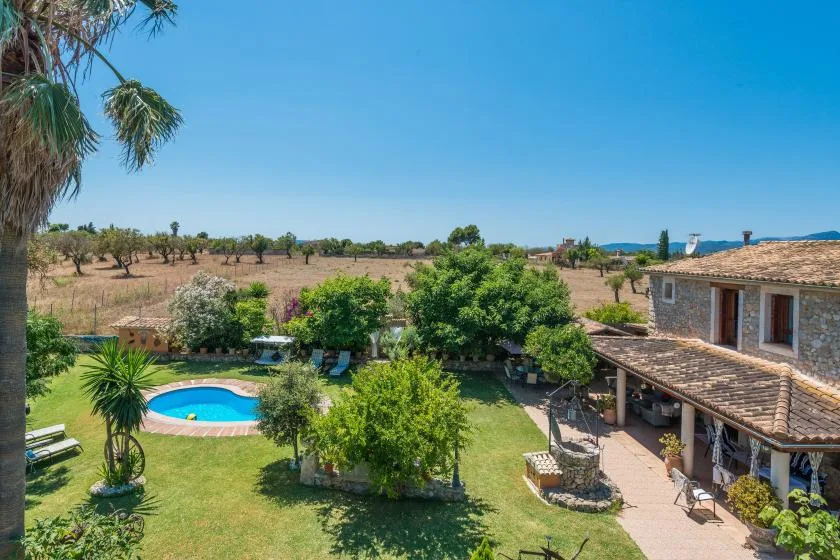 A garden and swimming pool beside a house, with open countryside beyond.