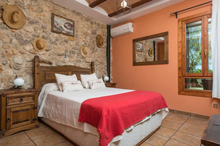 A bedroom with a bed covered in white bedding and a red blanket.