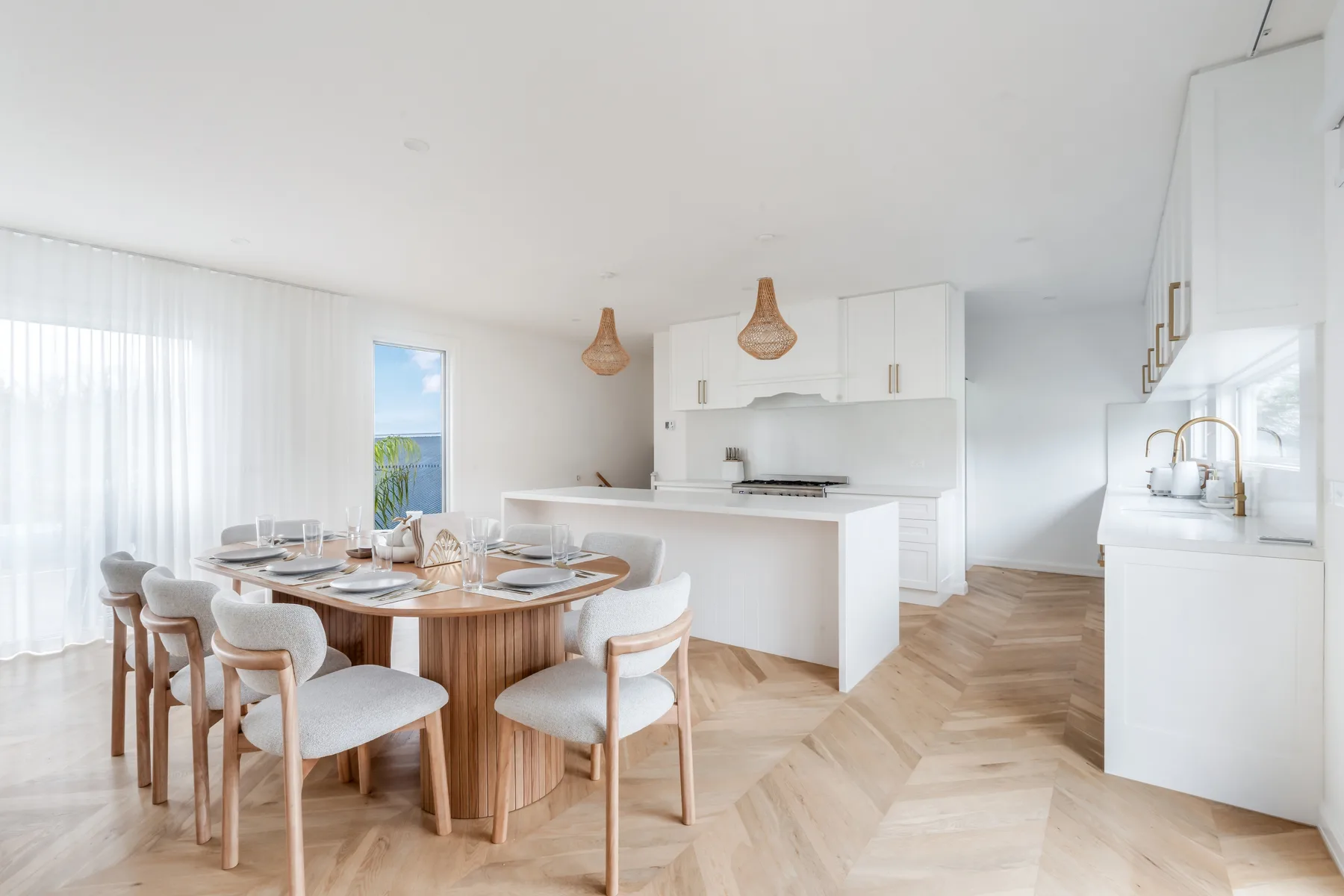 A dining area with a wooden table and chairs sits beside an open kitchen.