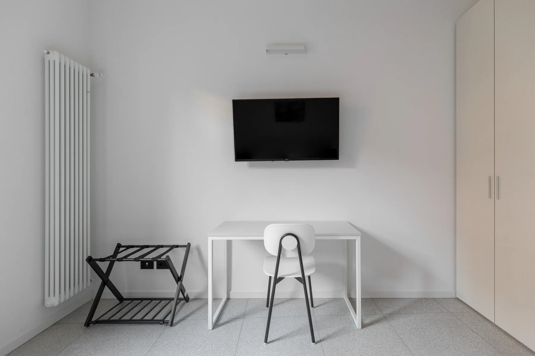 Una sencilla zona de escritorio con una silla y un televisor en la pared.