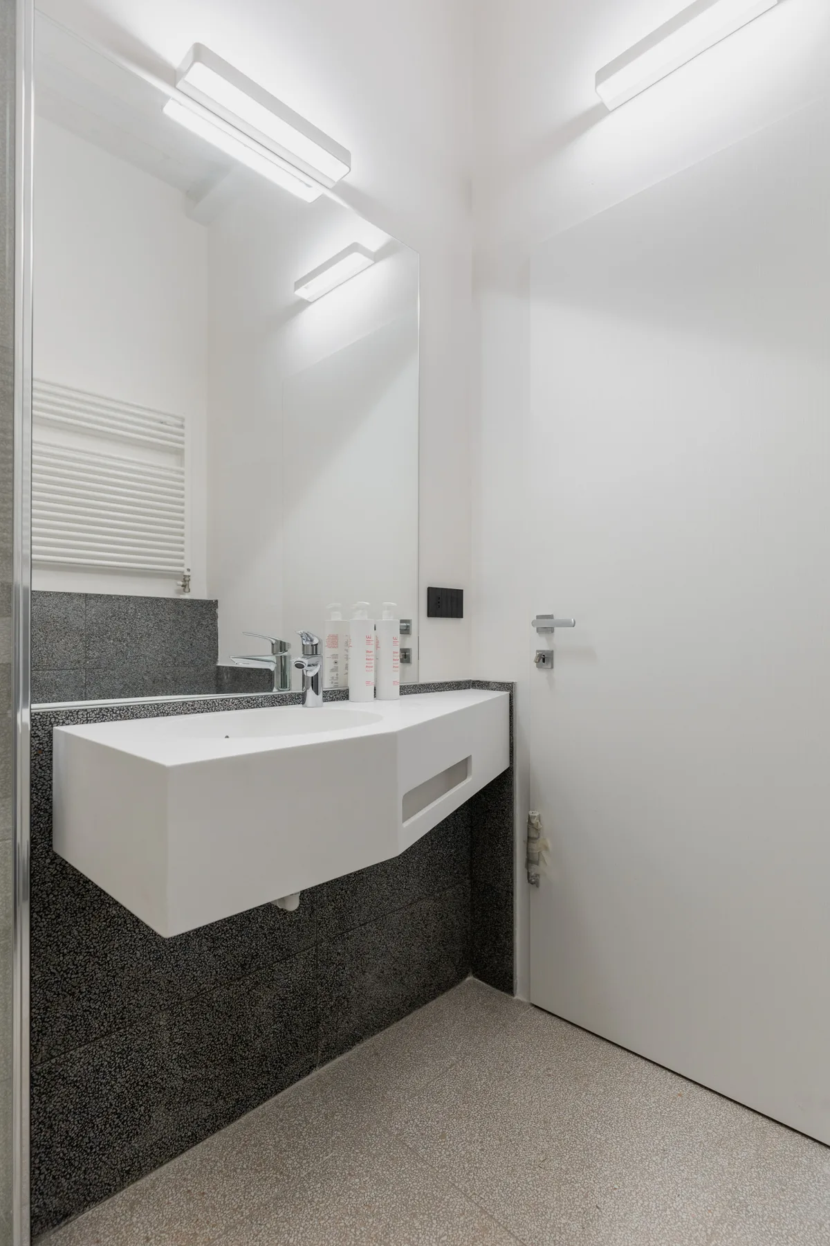 Un baño luminoso con un lavabo suspendido y un espejo grande.