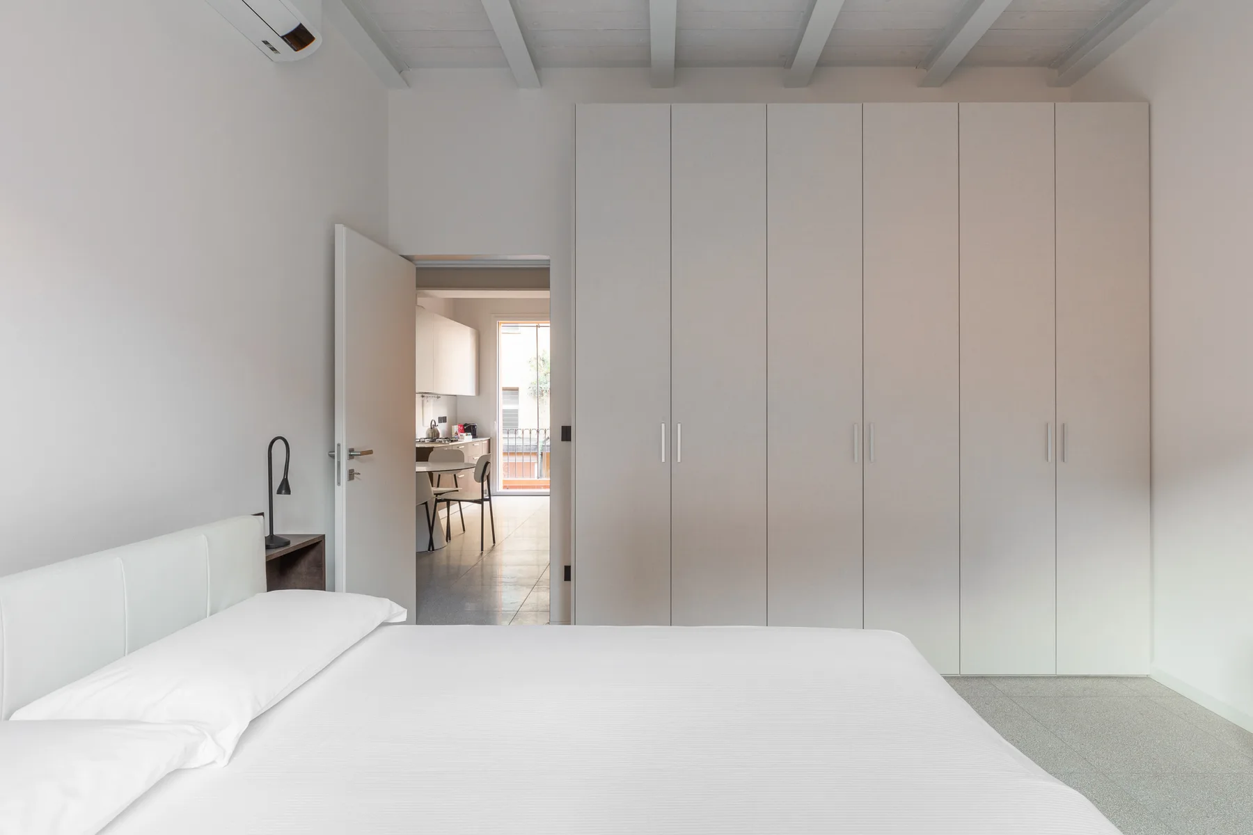 Un dormitorio luminoso con una cama blanca y armarios empotrados.