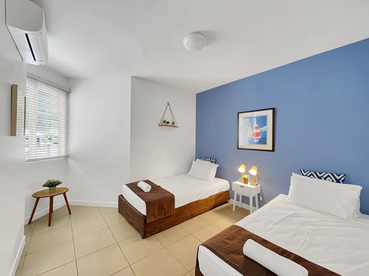 Un dormitorio con dos camas, ropa de cama blanca y una pared azul.