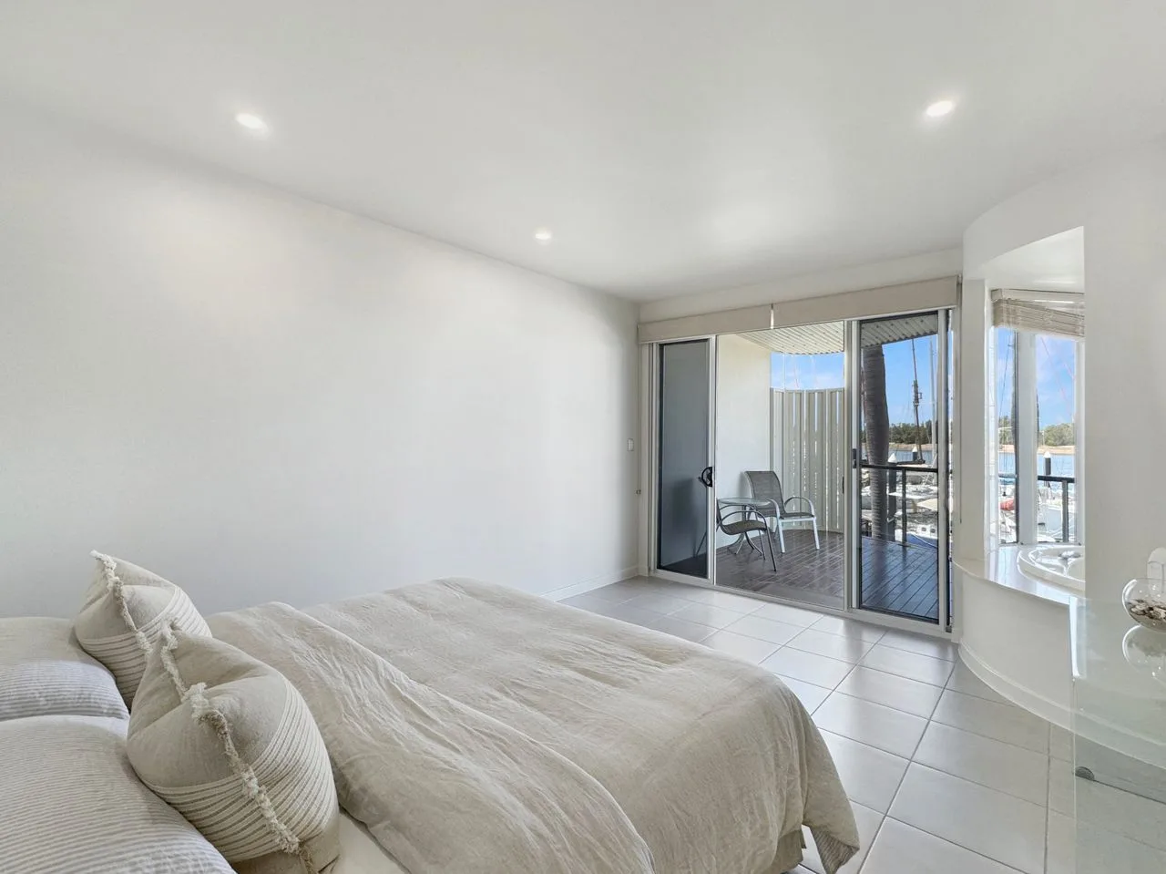 Un dormitorio luminoso se abre a un balcón mediante puertas corredizas de vidrio.