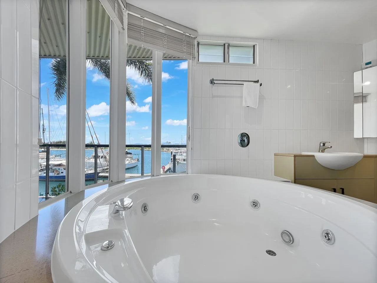 Un baño luminoso cuenta con una amplia bañera blanca junto a ventanas con vistas al agua.