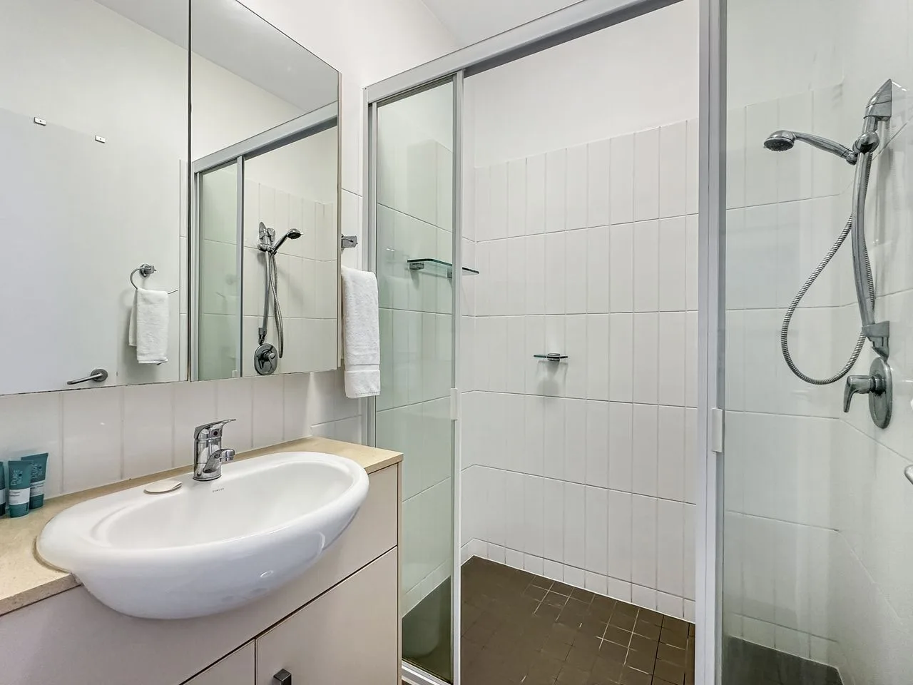 Un baño con azulejos, lavabo, espejo y ducha.