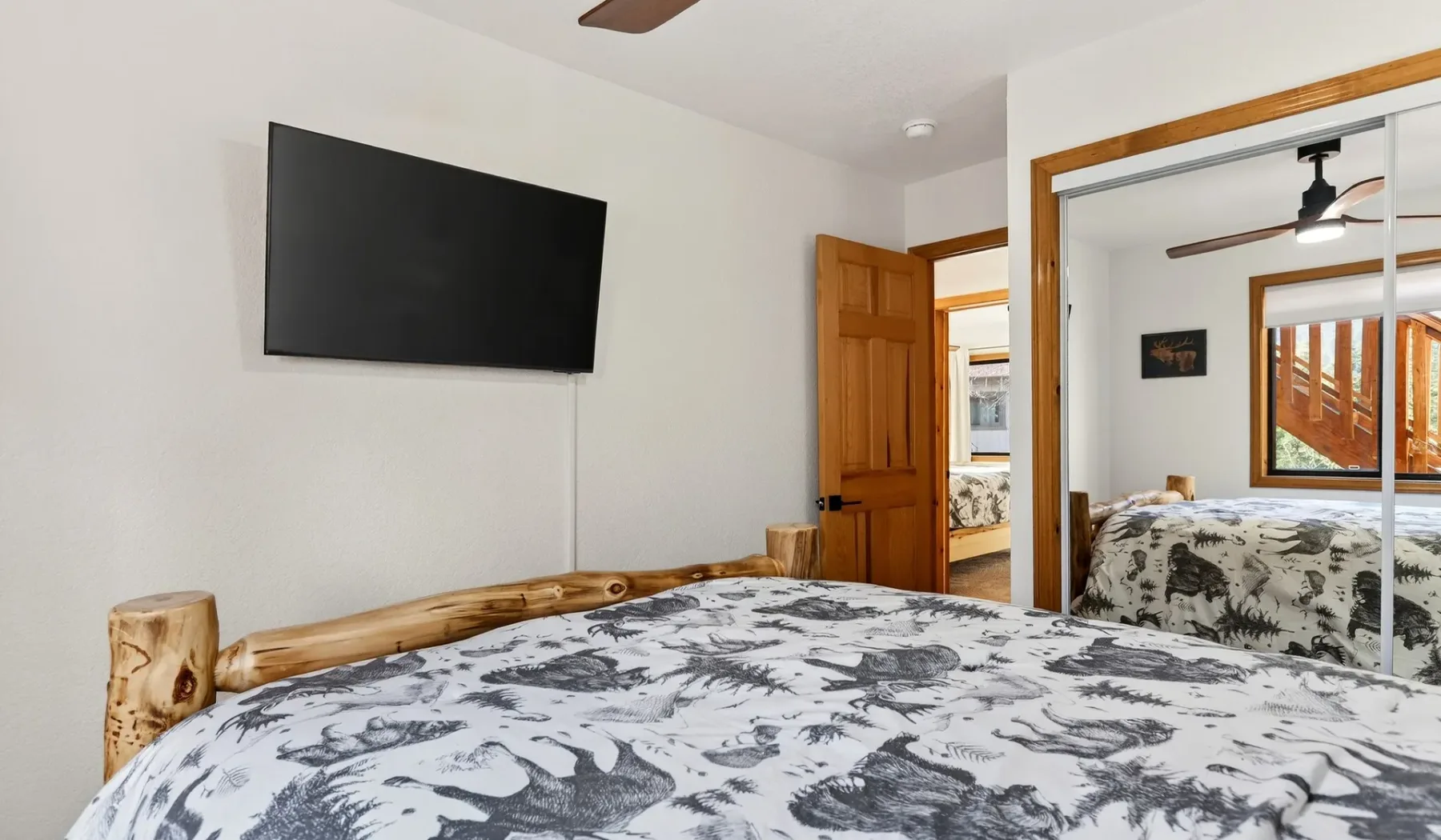 A bedroom with a patterned bedspread and a television mounted on the wall.