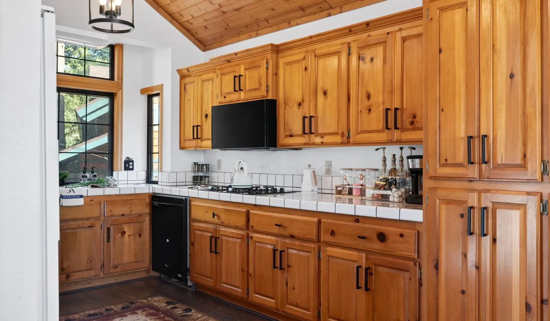 A kitchen with wooden cabinets, a white countertop, and a gas cooktop.