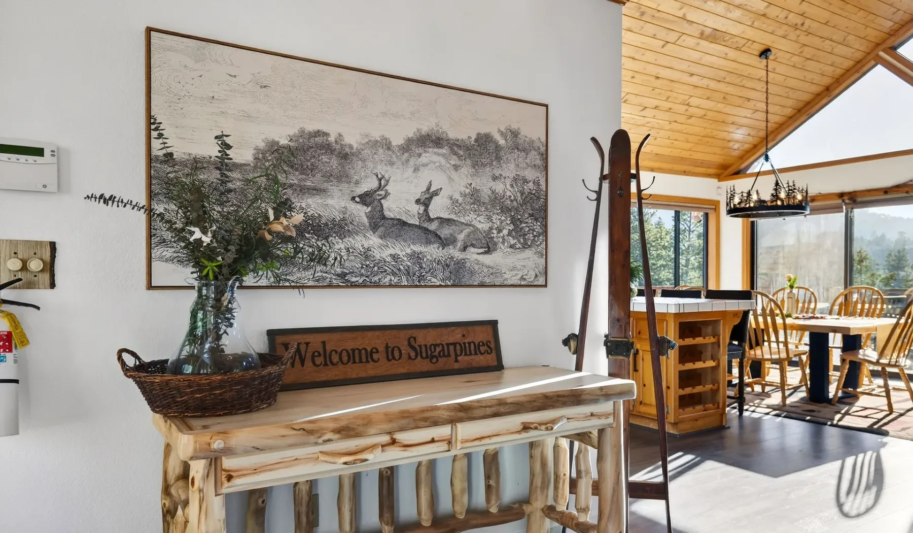 A rustic dining area with wooden tables and chairs beneath a sloped wood ceiling.