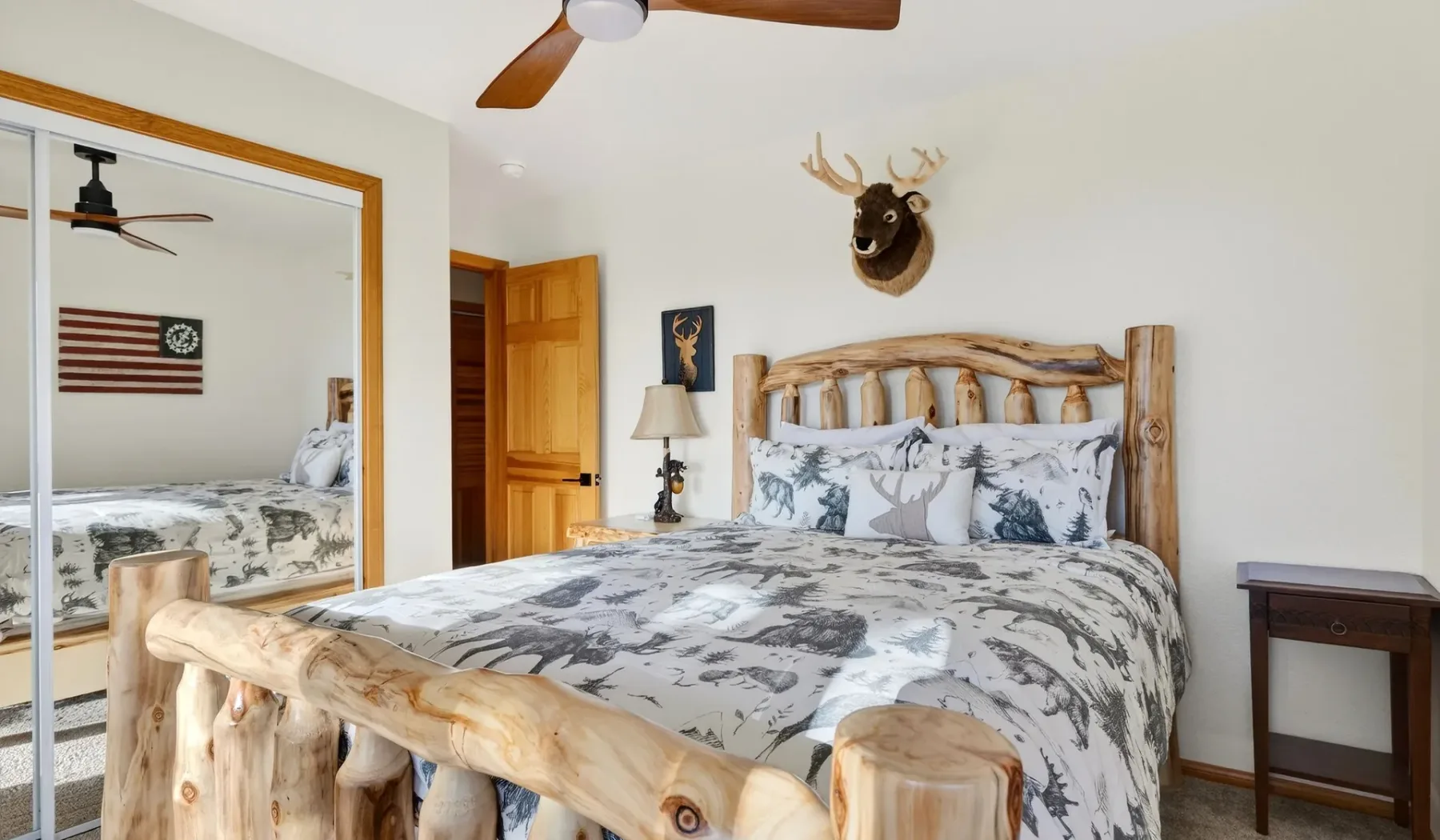 A bedroom with a log bed, patterned bedding, and a ceiling fan.