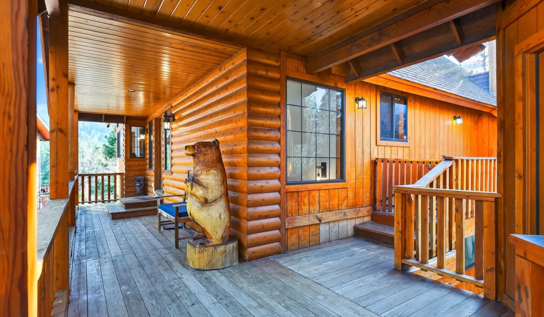 A covered wooden porch with railings and log walls.