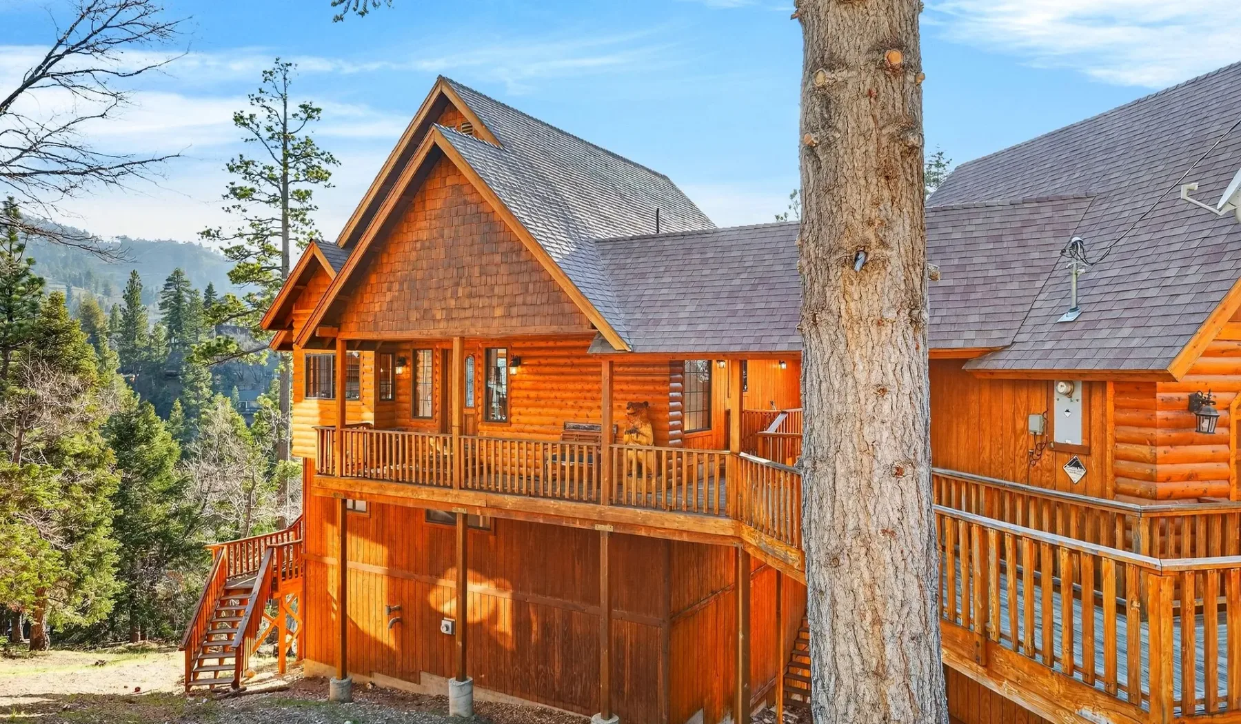 A large wooden cabin with wraparound balconies stands among trees.