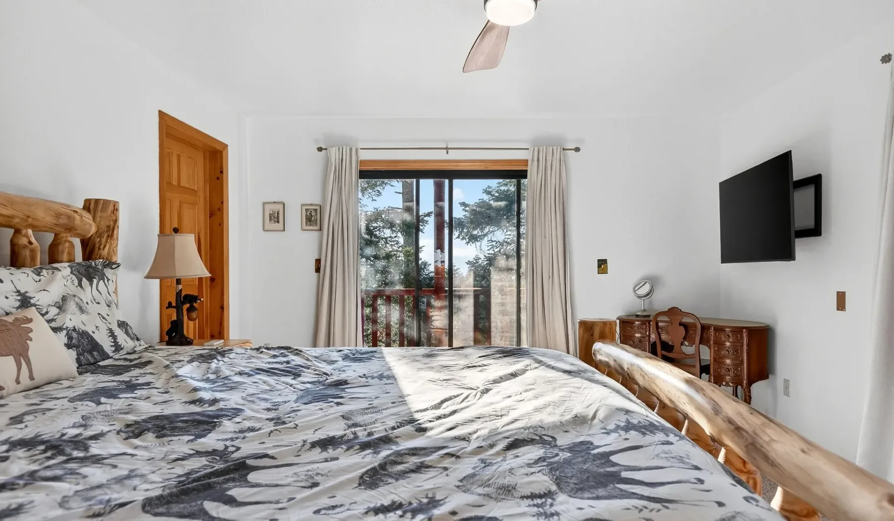 A bedroom with a large bed facing a window and glass doors.