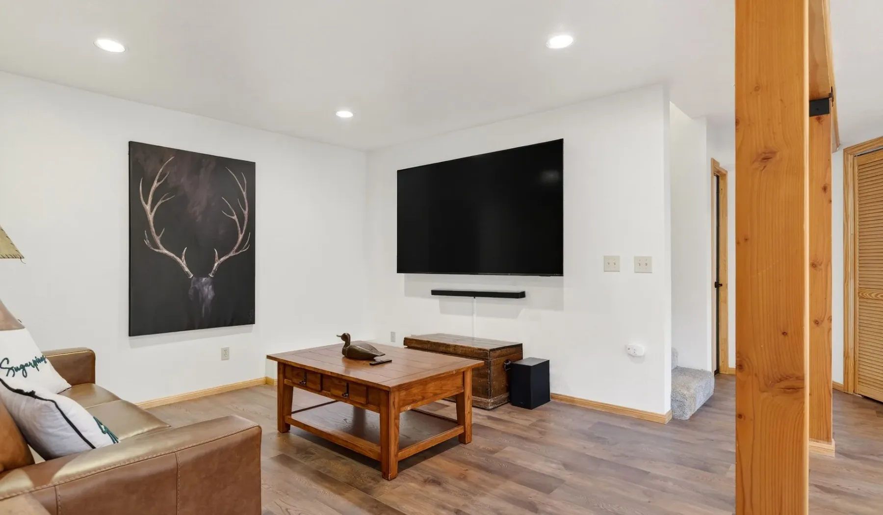 A bright living room with a wall-mounted television and wooden coffee table.