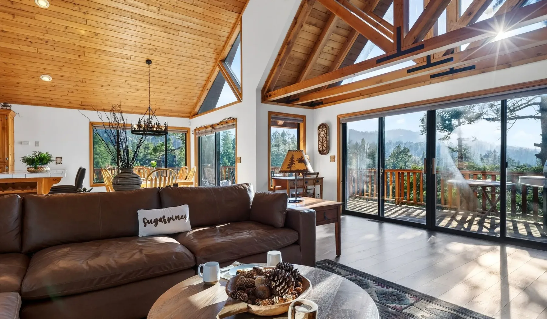 A bright living room with vaulted wood ceilings and large glass doors opening to a deck.