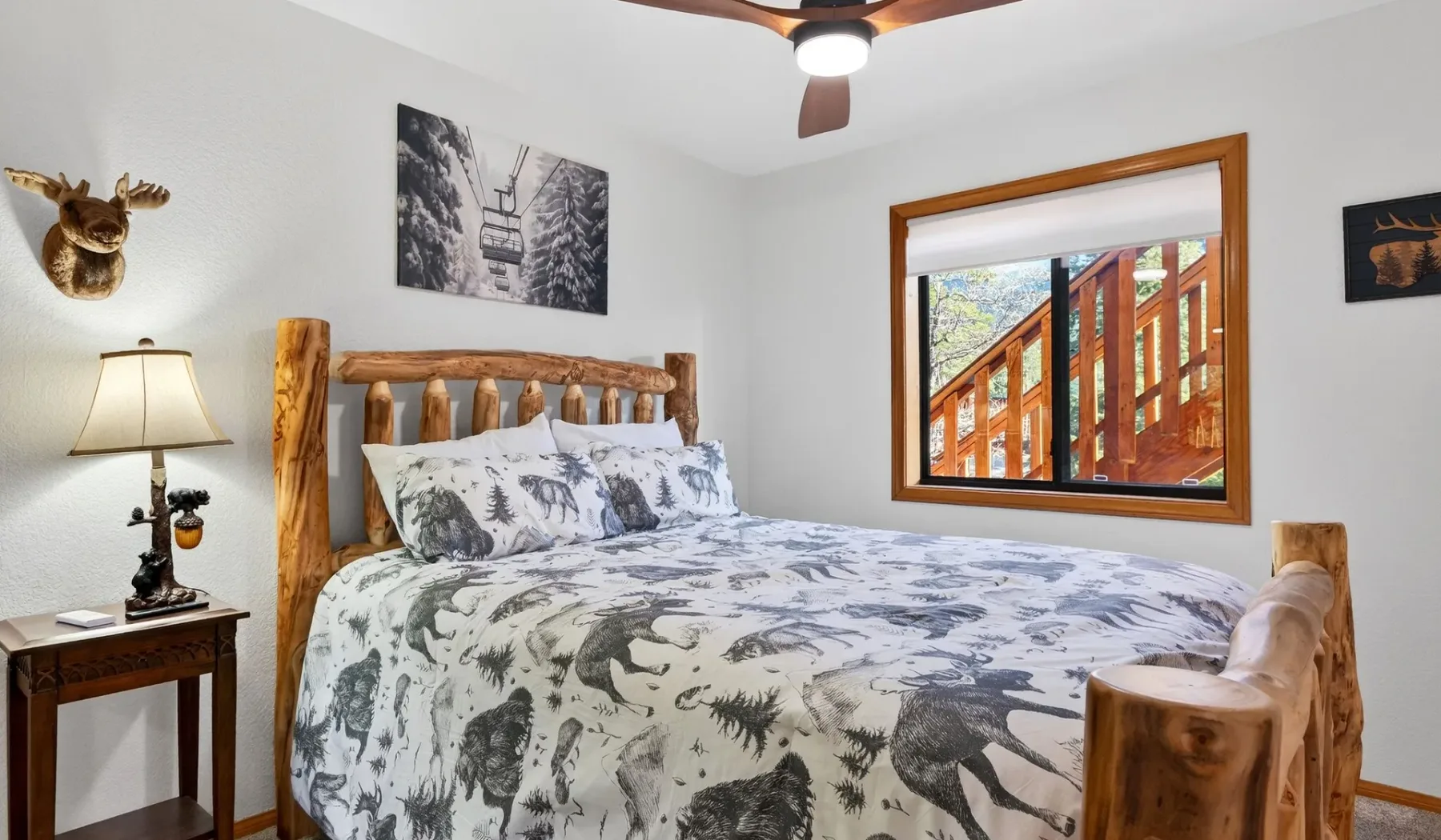 A bedroom with a large bed covered in a wildlife-patterned quilt and a window.
