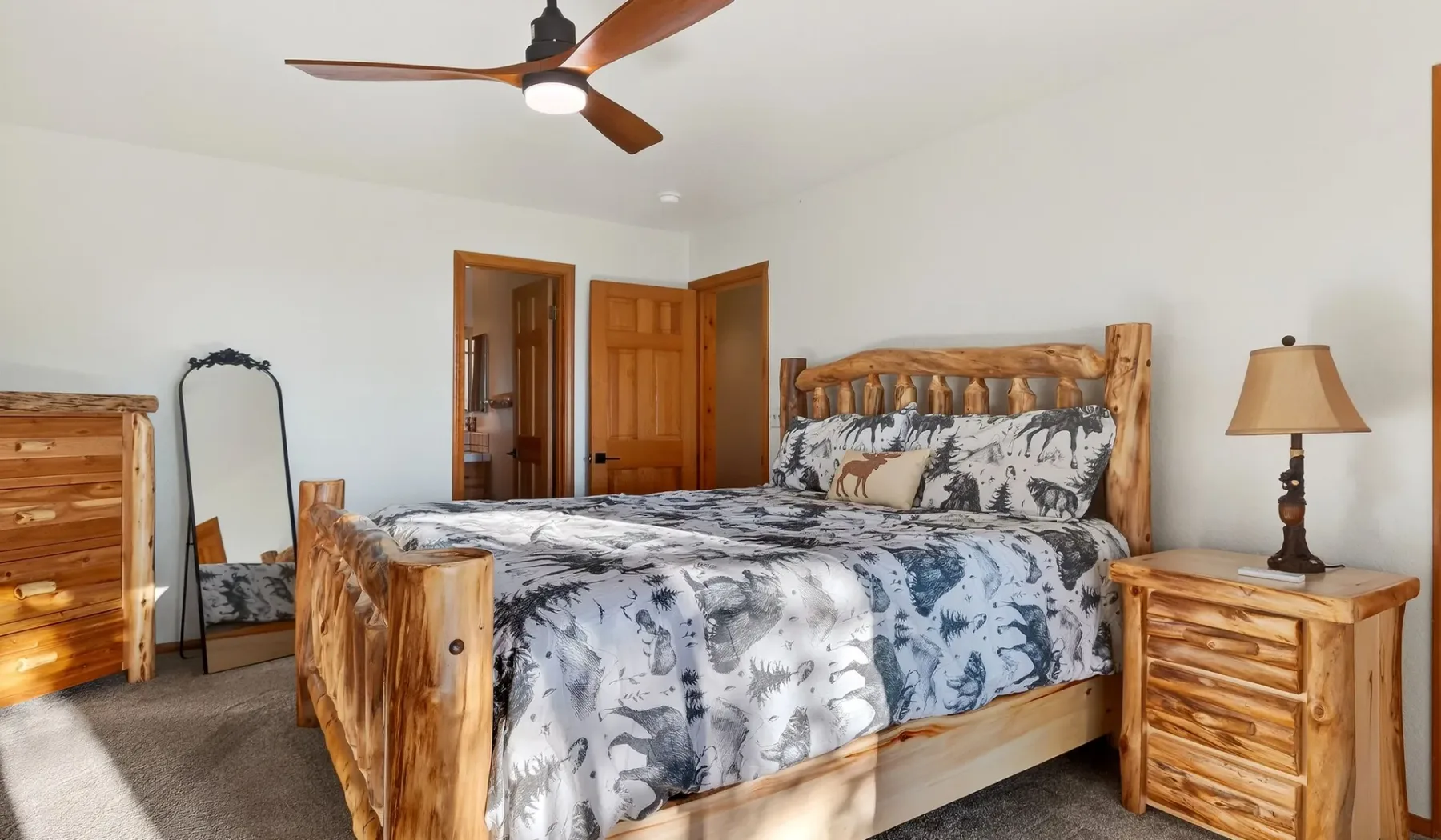 A bedroom with a wooden bed, patterned bedding, and a ceiling fan.
