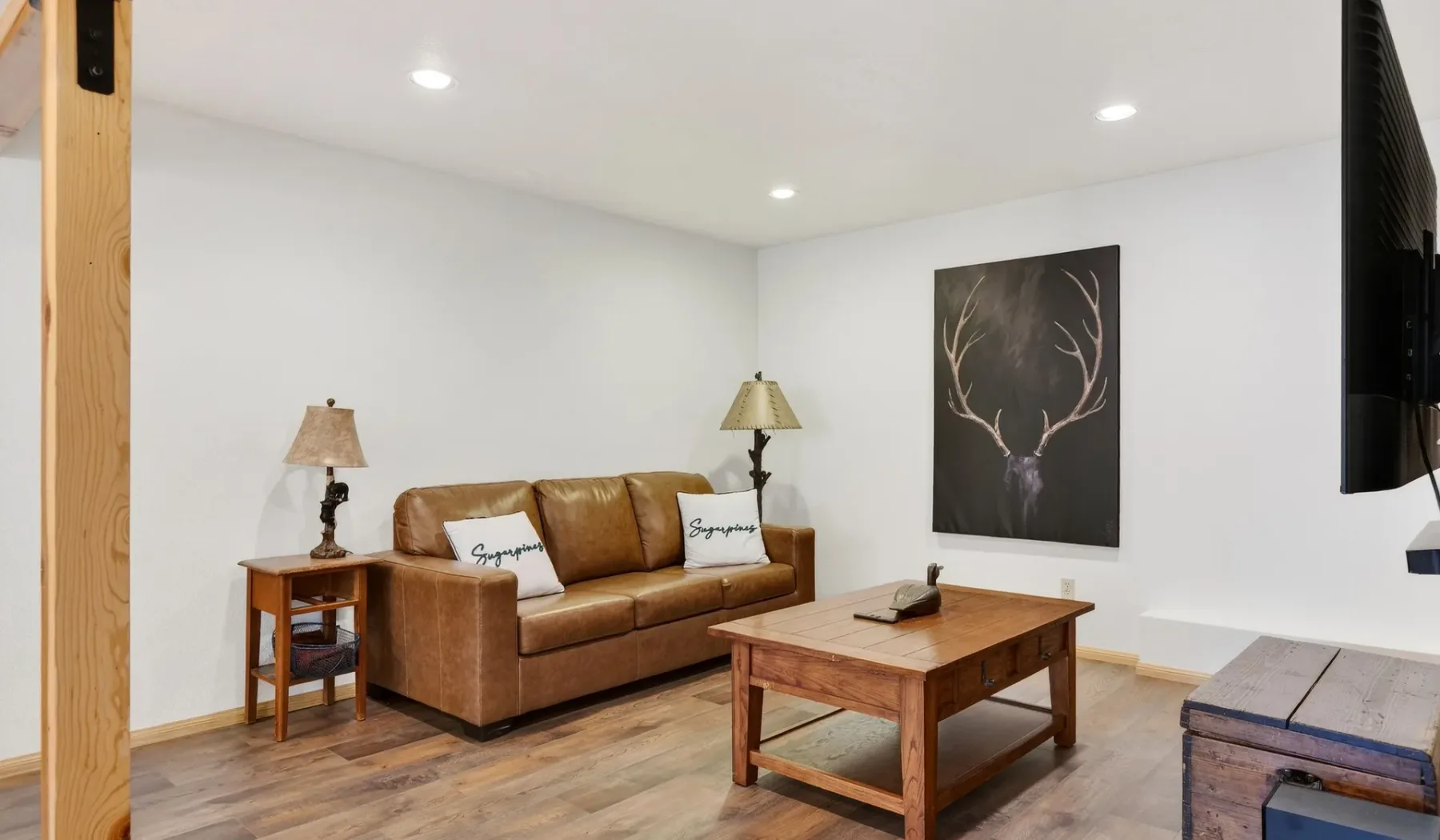 A living room with a brown sofa, wooden coffee table, and framed wall art.