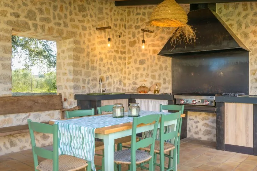 A rustic dining area with a green table and a large kitchen hood.