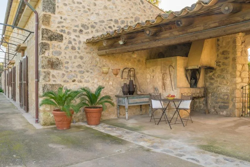 A stone courtyard with a covered outdoor dining area and potted plants.