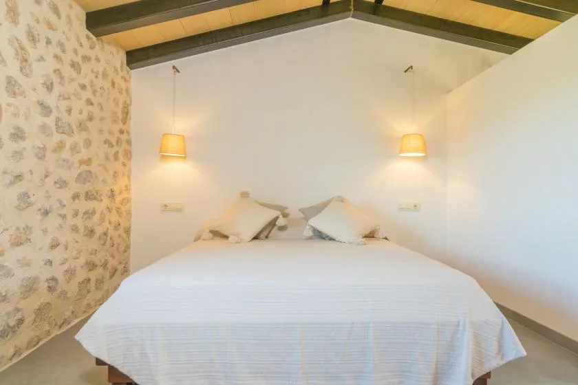 A bedroom with a neatly made bed beneath a sloped ceiling.