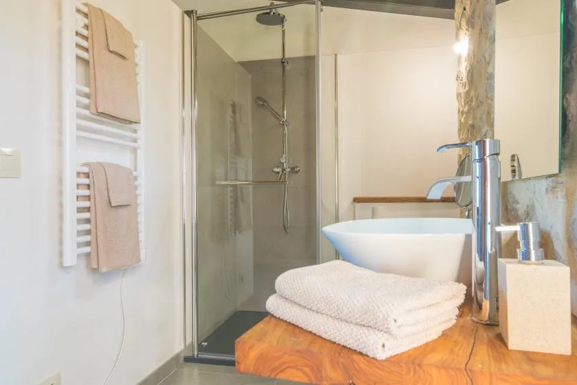 A bright bathroom with a glass shower and a white freestanding bathtub.