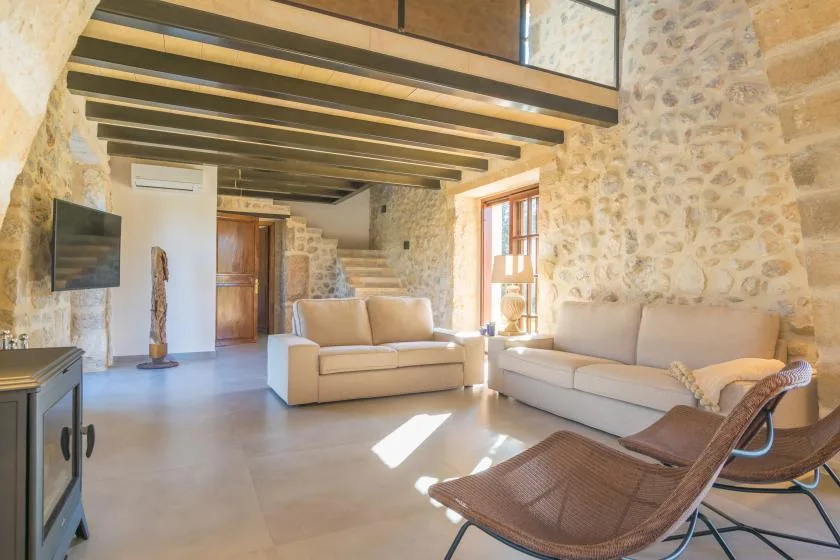 A stone-walled living room with pale seating and exposed ceiling beams.