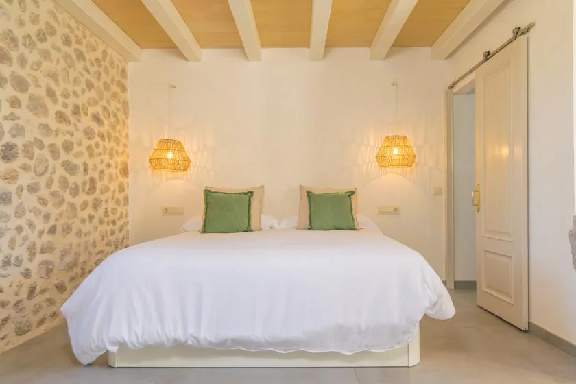 A bedroom with a bed, green pillows, and matching wall lamps.