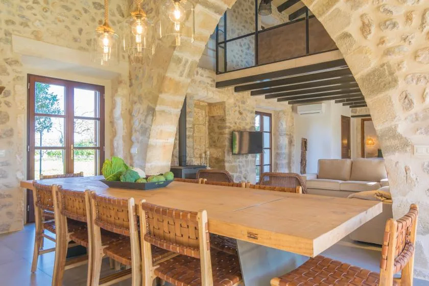 A stone-walled dining and living area with a long wooden table and seating.