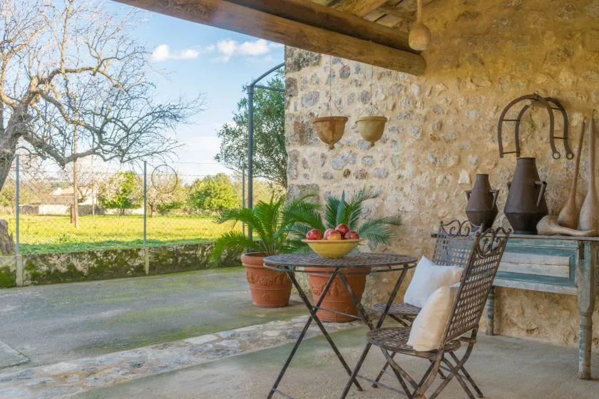 A stone patio with a small table and seating overlooks a green garden.