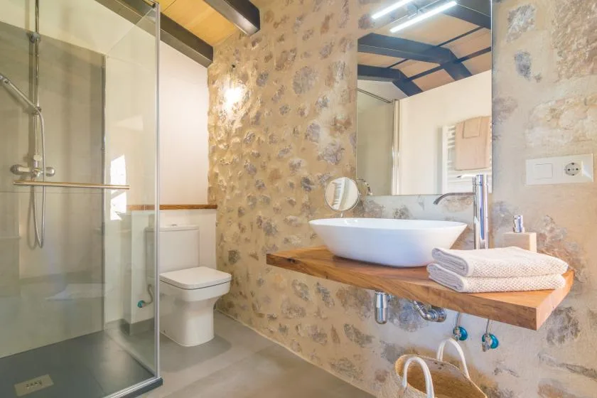 A bathroom with a glass shower and a sink on a wooden counter.