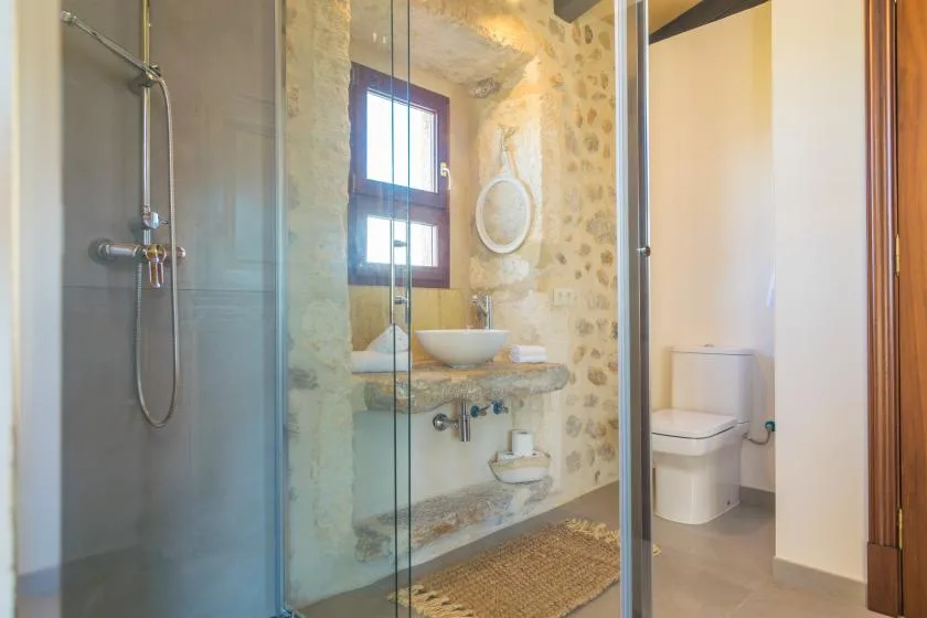 A bathroom with a glass shower, a sink, and a toilet.