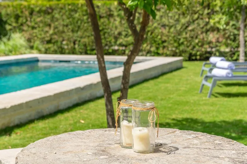 A garden seating area beside a swimming pool, with candles on a stone table.